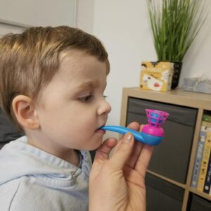 Terapeuta logopedyczny wspiera dziecko w ćwiczeniach oddechowych z użyciem dmuchajki