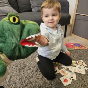Chłopiec podczas zabawy logopedycznej z pacynką i kartami obrazkowymi